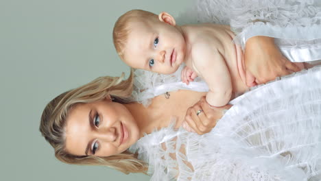 beautiful mother with adorable smiling child. cute naked infant baby looks curiously at camera. vertical screen.