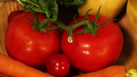 a colorful assortment of carrots, tomatoes, squash, and leafy greens arranged on a wooden surface.