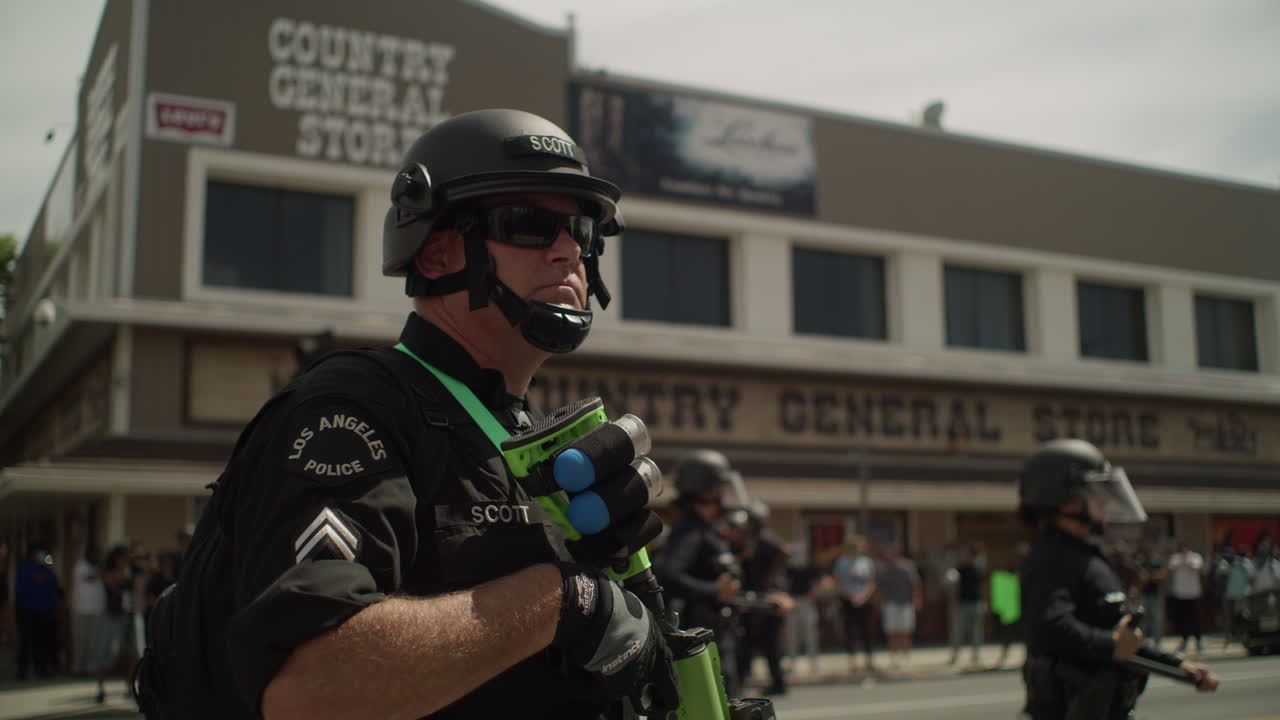 Police officer armed with a shotgun during a protest in front of the city hall