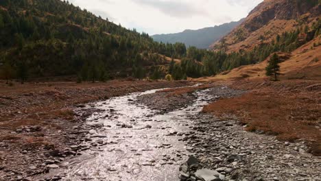 Colorful-Mountain-Landscape-With-Water-Stream-Flowing-On-Sunny-Autumn-Day---drone-shot