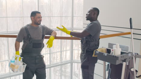 and arabic cleaning men wearing gloves and uniform talking near a cart cleaning