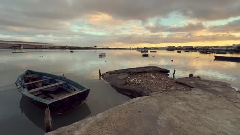 sunset over a river with boats and a broken pier