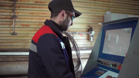 worker operating industrial machine control panel