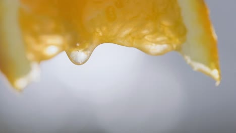 macro shot, squeezing orange slice, juice drops falling in slow motion