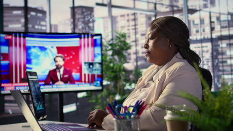 businesswoman working in office, watching news on television