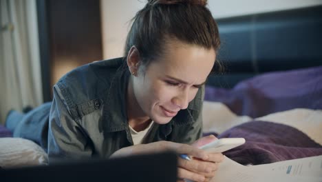 woman with phone lying on sofa at home. pretty woman typing message on telephone