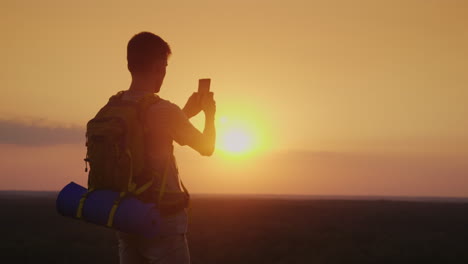 Ein-Junger-Mann-Mit-Rucksack-Fotografiert-Eine-Schöne-Landschaft-Bei-Sonnenuntergang-Silhouette-Auf-Oran