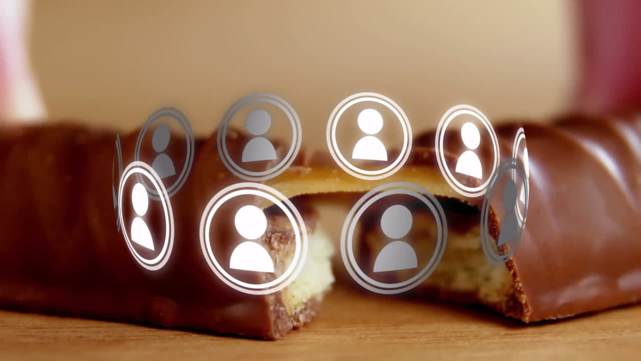 Floating digital user icons over chocolate bar on wooden surface in animation