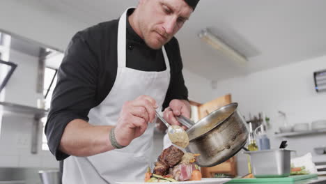 cocinero caucásico derramando salsa en la comida en la cocina, en cámara lenta