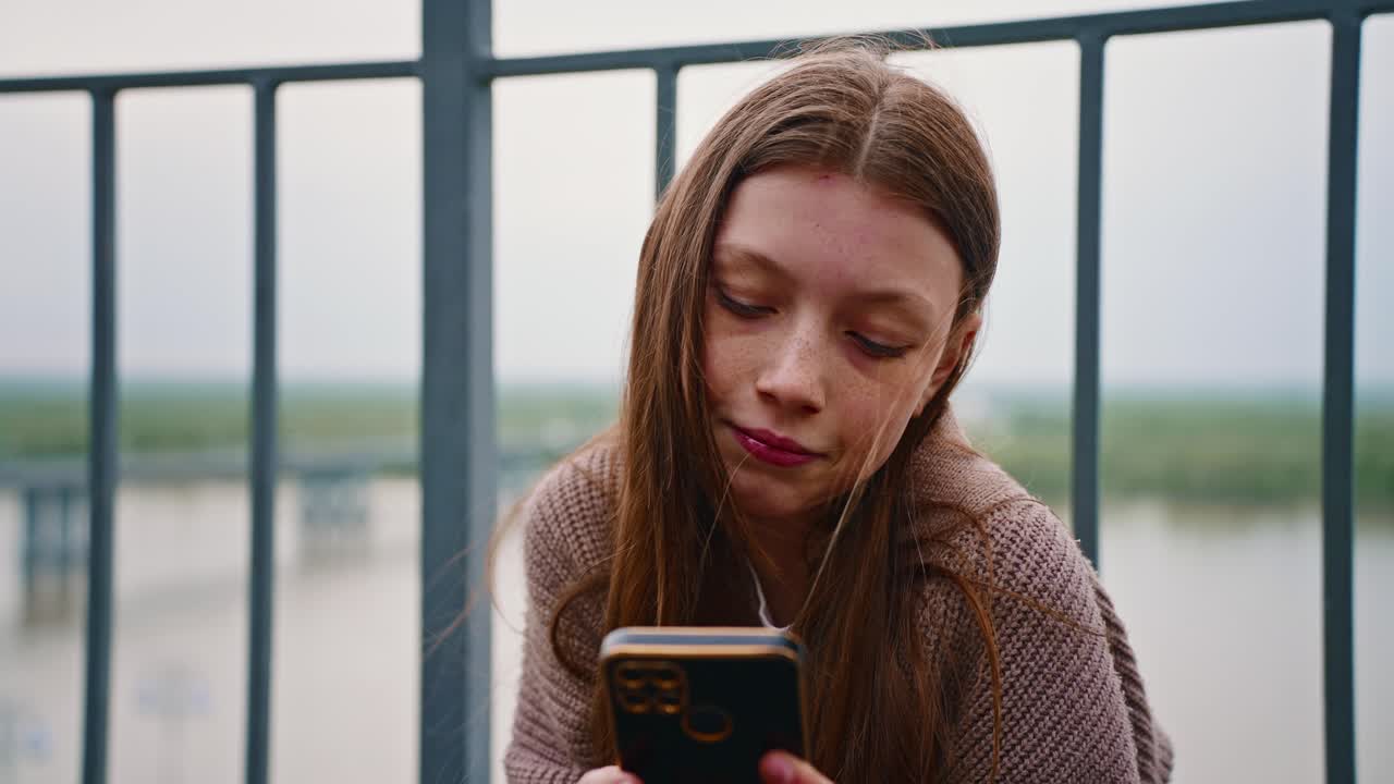 Adolescente Usando o Celular em um Mirante de Ponte