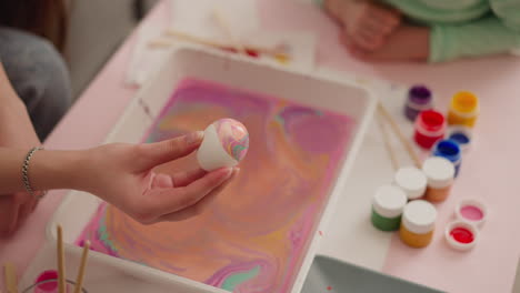 teenage girl holds easter egg with colored marbling patterns