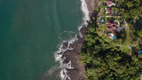 top down camera aerial 4k drone shot of rocky beach with wavy sea in tambor, costa rica