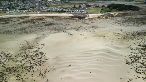 pan aérea delantera de la playa de arena con casas en la isla de île-grande