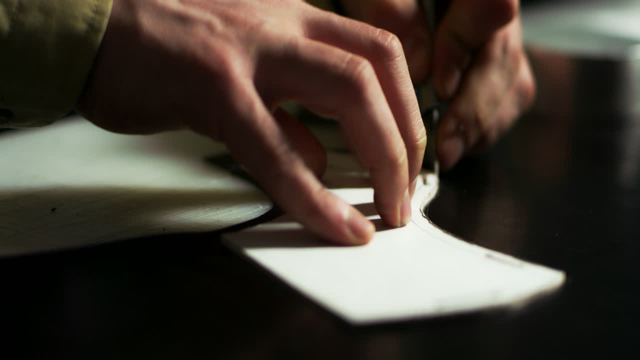 Close up craftsman hands cut out by template leather blank