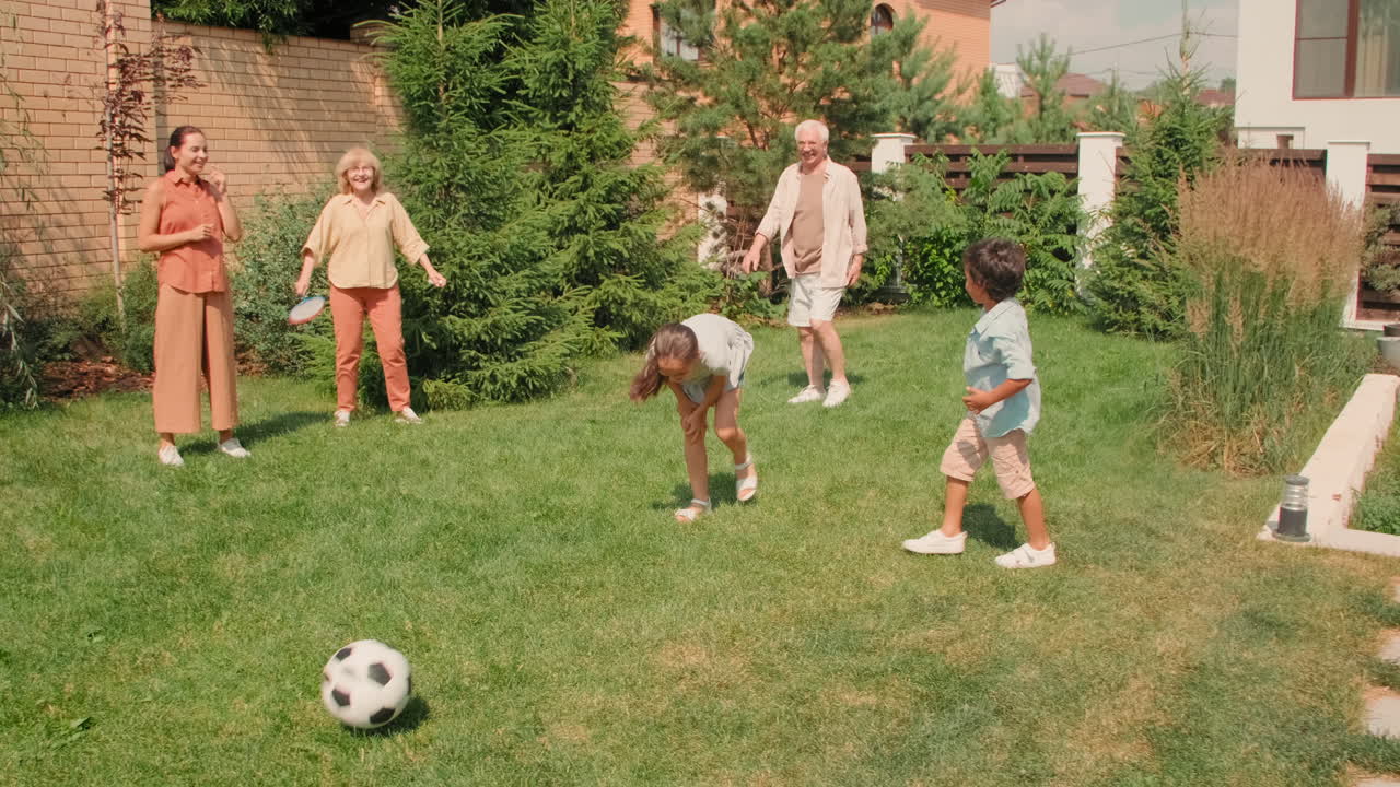 Active Family Of Six Playing Football In Backyard