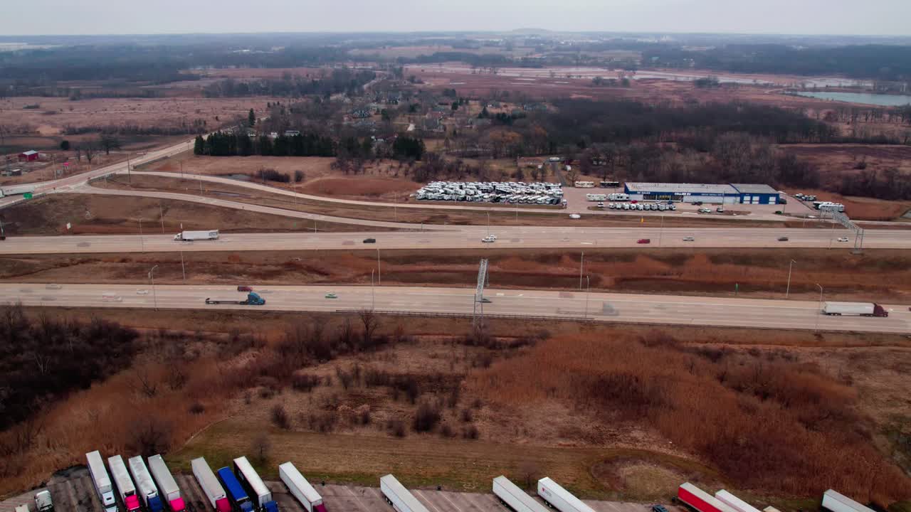 Timelapse of I-94 highway above a truck stop with semi trucks aligned and parked