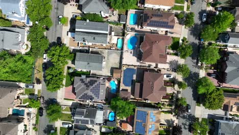 aerial top down shot showing american neighborhood with private swimming pool and solar panels on roof - circling drone flight