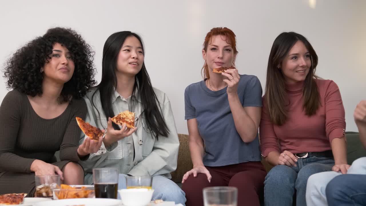 Diverse friends cheering up for woman bringing pizzas during weekend party at home