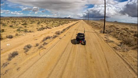 chasing an atv dune buggy along a mojave desert dirt road with a first-person view drone