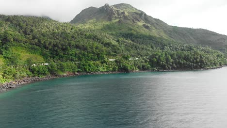 Antena-De-Drones-Volando-Sobre-El-Océano-Azul-Cerca-De-Una-Isla-Tropical-En-Asia-Con-Un-Volcán-En-El-Fondo-Y-Palmeras