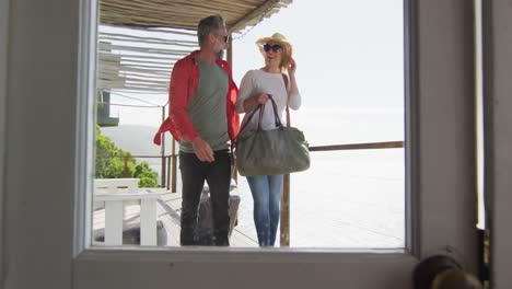 happy cacusia mature couple coming with suitcases to hotel room