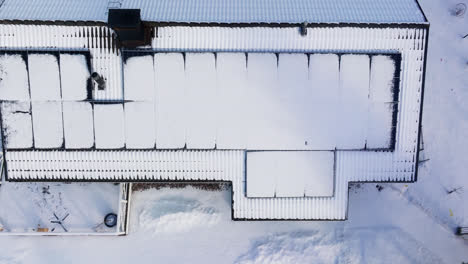 aerial top down shot rising above solar cells on a melting house roof, winter day