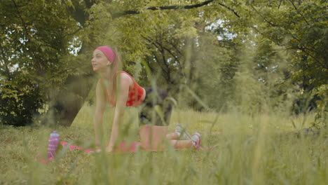 Chica-Atlética-Y-Deportiva-Haciendo-Ejercicio-En-El-Parque-Sobre-Una-Alfombra-Deportiva-Realizando-Entrenamiento-De-Yoga,-Pose-De-Tabla