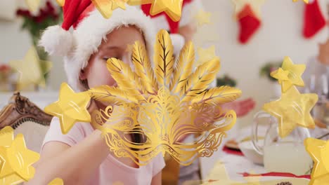 animation of carnival mask and stars over caucasian family with santa hats having christmas dinner