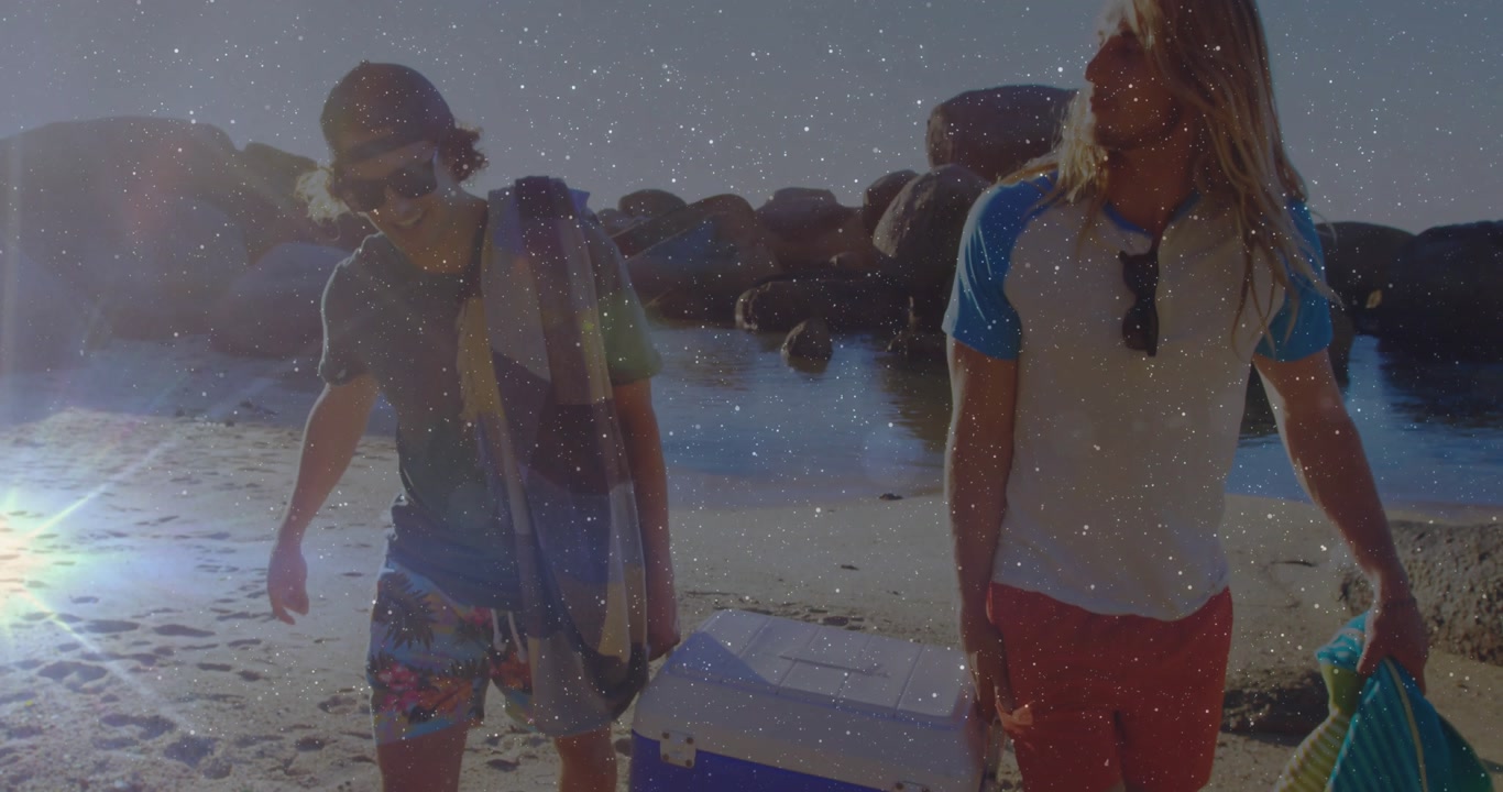 Two men walking across sand carrying blue-white cooler plus striped towel creating travel marketing