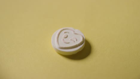 mano recogiendo caramelos de corazón con emoji guiñando un ojo sobre fondo amarillo