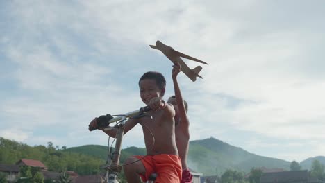 children playing with paper airplane on a bicycle
