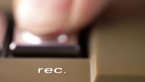 record button of a vintage tape recorder pressed by a finger macro