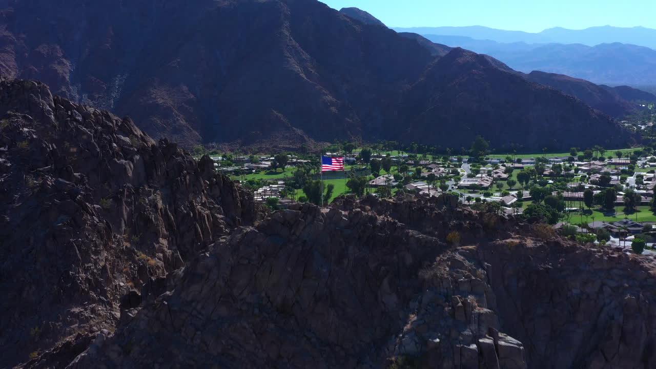 아름다운 럭셔리 골프 코스와 빨간 지붕 집 위의 산 꼭대기에 미국 국기가 바람에 펄럭입니다.