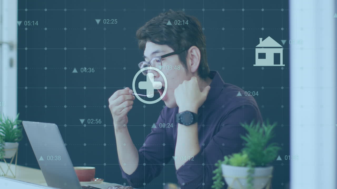 animación de números y iconos cambiantes sobre hombre asiático mirando la computadora portátil mientras come postre