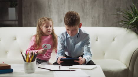 Schoolboy-with-little-sister-watch-online-lesson-at-home