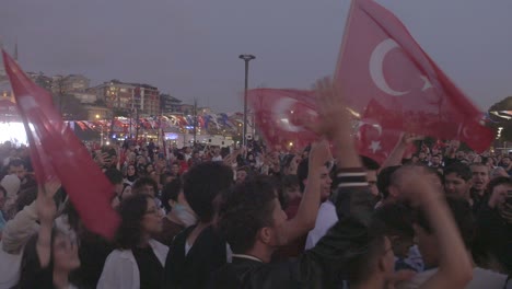 crowd of people waving turkish flags during a celebration in the city at night