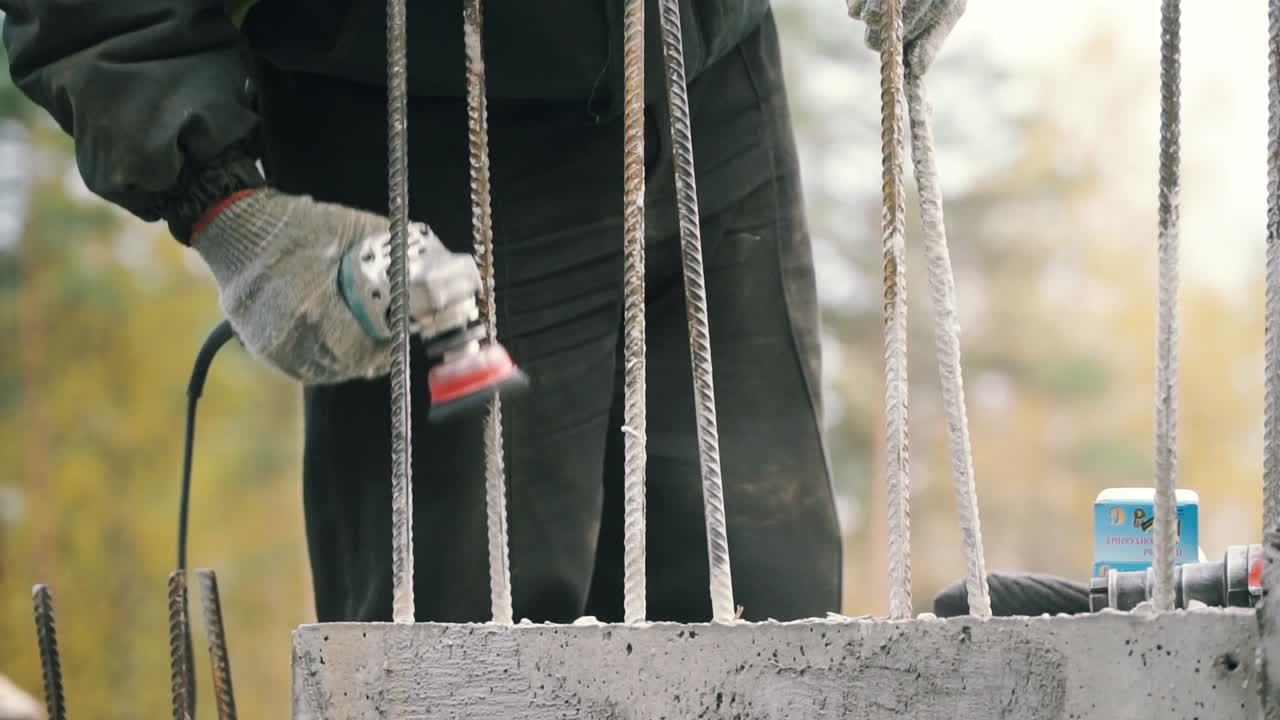 Construction worker using a grinder on reinforcing steel bars