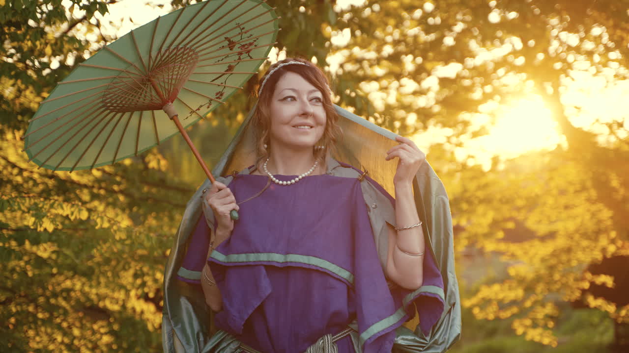 Woman in historical costume with umbrella at sunset