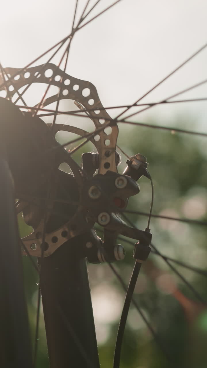 primer plano de la rueda de la bicicleta girando a medida que la luz del sol crea un hermoso efecto, proyectando un brillo cálido y un movimiento dinámico a través de los rayos