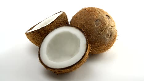 ripe tropical coconut and two halves of coconut rotating on a white background. tropical fruits, loopable