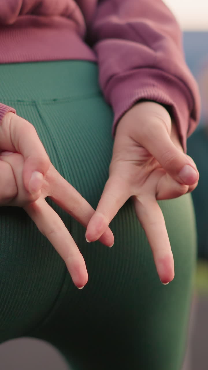 vista de las nalgas de cerca de la dama ligeramente doblada con la mano apuntando con una ligera vista de otras damas en el fondo involucradas en ejercicios de fitness o estiramiento al aire libre