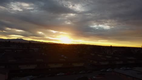 Drone-Disparó-Sobre-La-Ciudad-Con-El-Amanecer-Sobre-Las-Nubes,-Plano-General