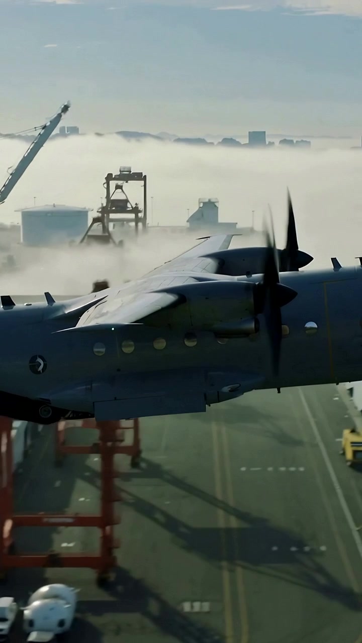 Video vertical: Turbopropulsor realizando un paso bajo sobre el puerto, revelando grúas y niebla.