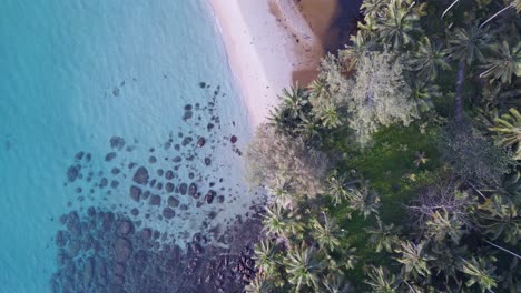 piedras negras en aguas cristalinas en la playa natural de taphao de arena rosa
