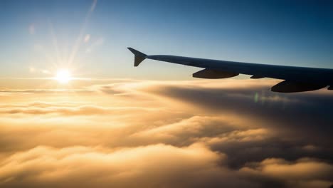airplane wing above clouds at sunrise or sunset