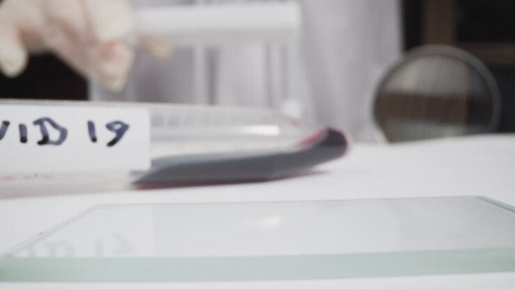 Tube with blood and tag Covid on table woman working in lab