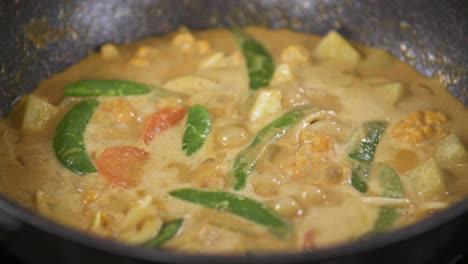 carrots and green peas cooking in a thai yellow coconut curry, vegetarian vegan thai food