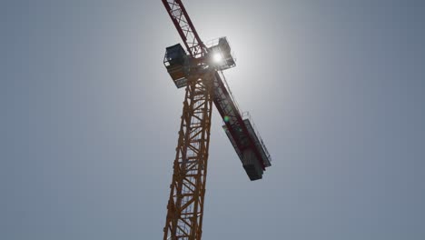 a majestic shot of a tower crane silhouetted against a bright sky, capturing the grandeur of this essential piece of machinery in the construction industry. the sun shines behind the crane
