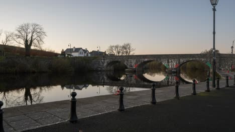 santo grial o lapso de tiempo de día a noche del pueblo de la ciudad con puente y luces de la calle a lo largo de un río en irlanda