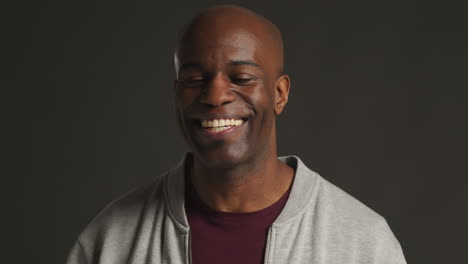 head and shoulders studio portrait of smiling and laughing mature man against black background